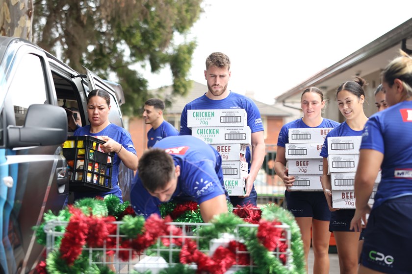 Bulldogs players unload a truck's worth of donated items at the Rev. Bill Crews Foundation site in Ashfield in support of a Christmas food drive appeal.