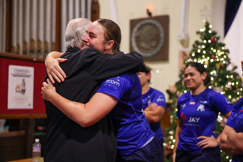 Rev. Bill Crews embraces Bulldogs Harvey Norman Women's player Tara McGrath West following the donation to the Foundation's Christmas Food Appeal